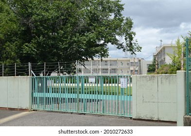 The School Gate Is Closed For Safety. You Can See The School Building In The Back.It Is Written In Japanese As 