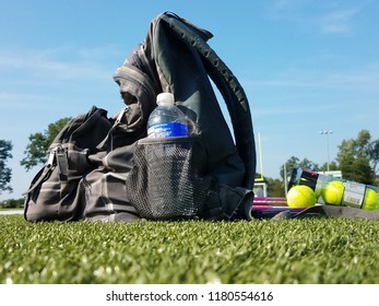 School Gear, A Tennis Racket, And Balls Sit On A Highschool Football Field As The School Season Has Returned.