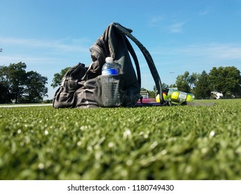 School Gear, A Tennis Racket, And Balls Sit On A Highschool Football Field As The School Season Returns.