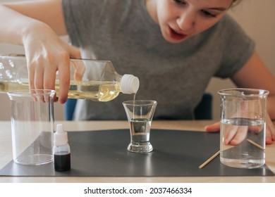 School Girl Doing Science Experiment With Water, Food Coloring, Oil And Aspirin. Step By Step Process Of Doing Homework Of Making Lava Lamp. Education, Back To School, Distant Concept.