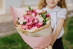 School Girl Dressed In School Uniform Holding A Bright Pink Festive Bouquet Of Beautiful Flowers For Teacher. No Face. Blurred Background.