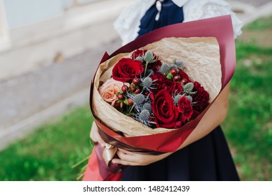 School Girl Dressed In School Uniform Holding A Bright, Festive Bouquet Of Beautiful Flowers For Teacher. Red Rose. No Face. Blurred Background.