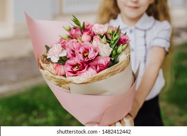 School Girl Dressed In School Uniform Holding A Bright Pink Festive Bouquet Of Beautiful Flowers For Teacher. No Face. Blurred Background.