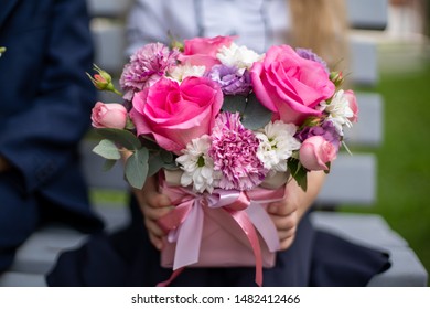 School Girl Dressed In School Uniform Holding A Bright Pink Festive Bouquet Of Beautiful Flowers For Teacher. No Face. Blurred Background.