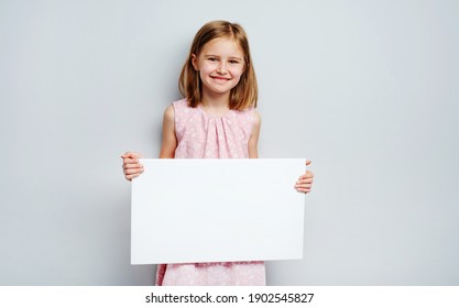 School Girl Holding Horizontal Blank White Poster On A Grey Wall Background