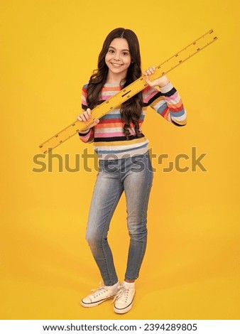 School girl holding measure for geometry lesson, isolated on yellow background. Measuring equipment. Student study math. Happy teenager, positive and smiling emotions of teen schoolgirl.