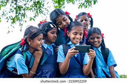 School Girl Kid Playing Video Game On Mobile Phone While Group Of Kids Surrounded - Concept Of Technology Addiction, Entertainment And Togetherness.