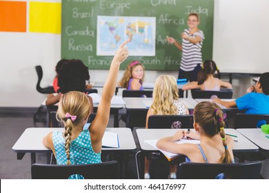 School Girl Raising Hand In Classroom At School