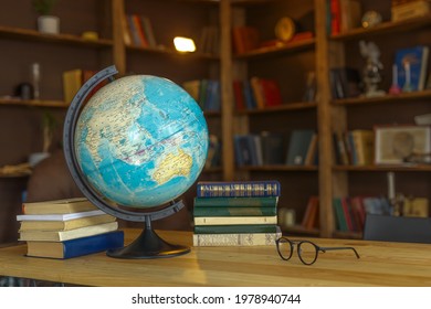 school globe stands on the table next to textbooks on the background of bookshelves, school background for photos - Shutterstock ID 1978940744