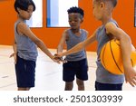 In school gym, boys in sportswear huddling with basketball, preparing for game. teamwork, training, gymnasium, huddle, energy, competition