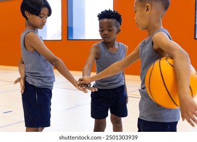 In school gym, boys in sportswear huddling with basketball, preparing for game. teamwork, training, gymnasium, huddle, energy, competition - Powered by Shutterstock