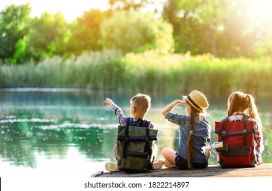 School Holidays. Group Of Children Sitting On Wooden Pier Near River 
