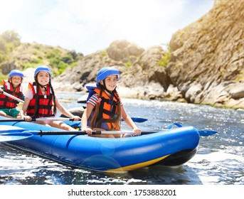 School Holidays. Group Of Happy Children Kayaking On River 