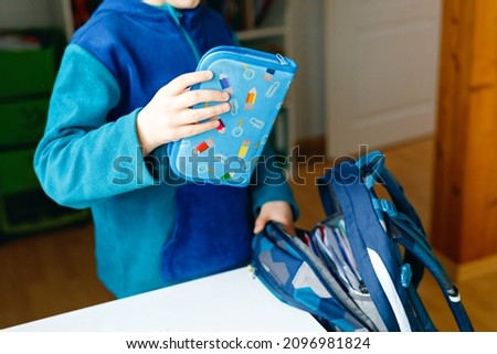 School kid boy getting ready in the morning for school. Healthy child filling satchel with books, pens, folders and school stuff. Preaparation, routine concept.