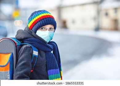 School Kid Boy With Glasses Wearing Medical Mask On The Way To School. Child Backpack Satchel. Schoolkid On Winter Day With Warm Clothes. Lockdown And Quarantine Time During Corona Pandemic Disease