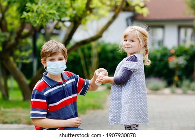 School Kid Boy Helping Little Toddler Sister Cleaning Hands With Sanitizer Spray. Brother And Cute Little Girl Learn Hygiene Rules. Family During Coronavirus And Flu Lockdown. Covid Virus Protection.