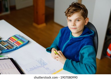 School kid boy learning at home with tablet for school. Adorable child making homework and using pad and modern gadgets. Home schooling and distance learn concept. Winter, sledging, skiing in German
