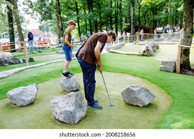 School Kid Boy Playing Mini Golf With Father. Happy Child And Dad, Young Man Having Fun With Outdoor Activity. Summer Sport For Children And Adults, Outdoors. Family Vacations Or Resort.