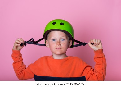 School Kid Boy Skateboarder Putting On Safety Helmet. Responsibility To Protect Yourself. Child Portrait Putting On Protective Equipment Before Skating On The Playground Or Street In City.