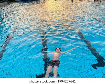 School Kid Boy Splashing In An Outdoor Swimming Pool On Warm Summer Day. Happy Healthy Preteen Child Enjoying Sunny Weather In City Public Pool. Kids Activity Outdoors With Water.