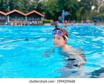 School Kid Boy Splashing In An Outdoor Swimming Pool On Warm Summer Day. Happy Healthy Preteen Child Enjoying Sunny Weather In City Public Pool. Kids Activity Outdoors With Water.