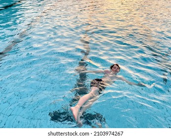 School Kid Boy Splashing In An Outdoor Swimming Pool On Warm Summer Day. Happy Healthy Preteen Child Enjoying Sunny Weather In City Public Pool. Kids Activity Outdoors With Water.