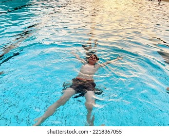 School Kid Boy Splashing In An Outdoor Swimming Pool On Warm Summer Day. Happy Healthy Preteen Child Enjoying Sunny Weather In City Public Pool. Kids Activity Outdoors With Water.