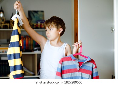 School Kid Boy Standing By Wardrobe With Clothes. Child Making Decision For School Shirt To Wear. Children Get Dressed In The Morning For School.