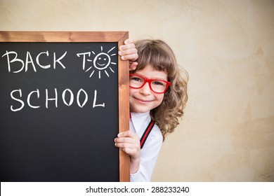 School Kid In Class. Happy Child Holding Blackboard Blank. Education Concept