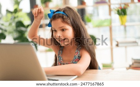 School kid, cute little girl having fun with laptop computer watching zoom video conference, movie. Child study from home. Homeschooling, network education, online learn, preschool concept image.