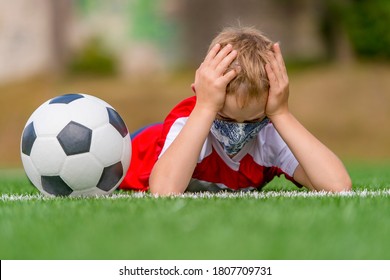 School Kid With Mask And Soccer Ball In A Physical Education Lesson. Safe Back To School During Pandemic Concept. Social Distancing To Fight COVID-19