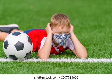 School Kid With Mask And Soccer Ball In A Physical Education Lesson. Safe Back To School During Pandemic Concept. Social Distancing To Fight COVID-19