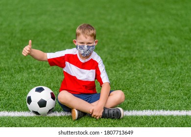 School Kid With Mask And Soccer Ball In A Physical Education Lesson. Safe Back To School During Pandemic Concept. Social Distancing To Fight COVID-19