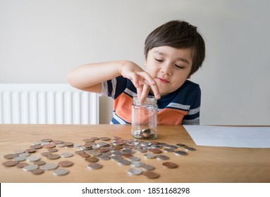 School Kid Putting Money Coins Into Clear Jar, Child Counting His Saving Money, Young Boy Holding Coin On His Hands, Children Learning About Saving For Future Concept