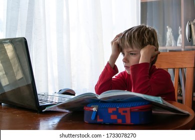 School kid in self isolation using laptop for homework, Social Distance learning online education during coronavirus epidemic. Cute boy studies and does school homework at home during quarantine