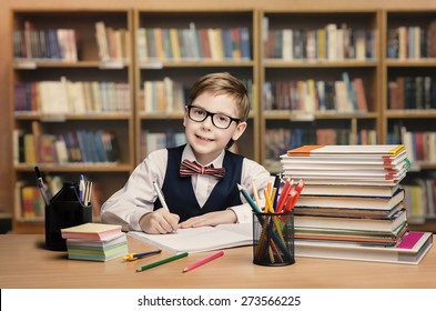 School Kid Studying In Library, Child Writing Paper Copy Book In Classroom With Shelves