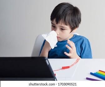 School Kid Wiping Nose With Tissue And Watching Cartoon On Tablet,Child Stay At Home During Corona Virus Home Quarantine,E-learning, Home Schooling ,Protective Measures Against Spreading Of Covid-19