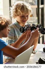 School Kids Boys Helping In Building Robotic Car Learning Together At STEM Class. Happy Students Children Studying Together Playing Making Robots In Classroom At Science And Coding Education Lesson.