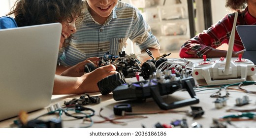 School kids boys helping building robotic car learning together at STEM class. Happy students children study together making robots in classroom at science and coding education lesson, close up view.