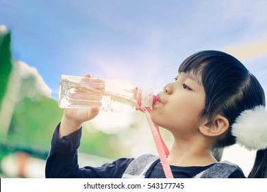 School Kids Drink Water From A Bottle Against The Background Sky.