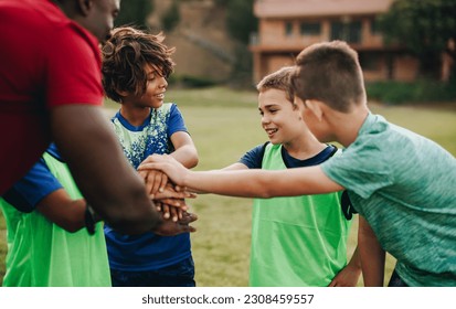 School kids having a huddle with their coach in a sports field. Rugby team having a motivational pep talk before practice. Sports coach mentoring children in elementary school. - Powered by Shutterstock