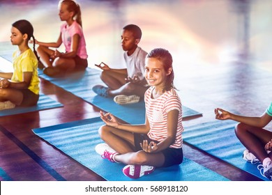 School kids meditating during yoga class in basketball court at school gym - Powered by Shutterstock