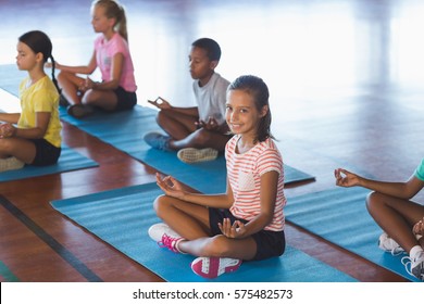 School Kids Meditating During Yoga Class In Basketball Court At School Gym