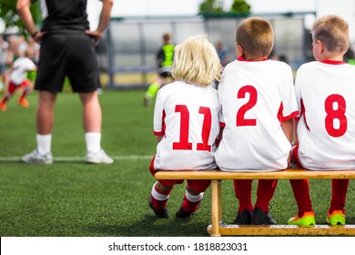 School Kids On Soccer Bench. Group Of School Boys With Coach On A Pitch Sideline On Soccer Football Tournament