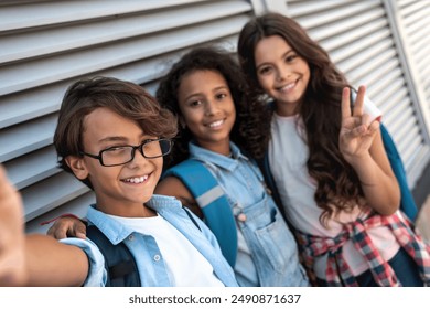 School kids preteen boys and girls pupils friends taking selfie from mobile phone using gadget outdoor at the street over grey background. Education, elementary school, technology concept - Powered by Shutterstock