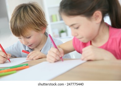 School Kids Sitting At Table And Writing On Paper