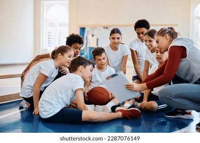 School kids and their sports teacher analyzing basketball exercise plan during PE class.  - Powered by Shutterstock