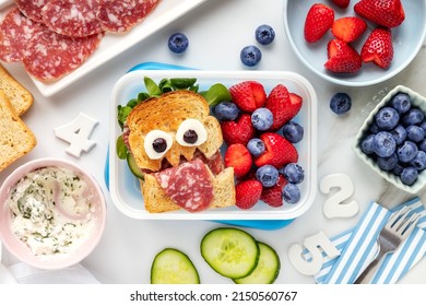 School Lunch Box With A Cute Monster Sandwich With Salami And Fresh Berries Like Strawberries And Blueberries. Overhead View Flat Lay