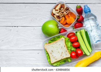 school lunch boxes with sandwich and fresh vegetables, bottle of water, nuts and fruits on white wooden background. healthy eating concept. top view with copy space - Powered by Shutterstock