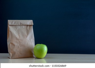 School lunch. Brown paper bag and  a green on blackboard background. - Powered by Shutterstock